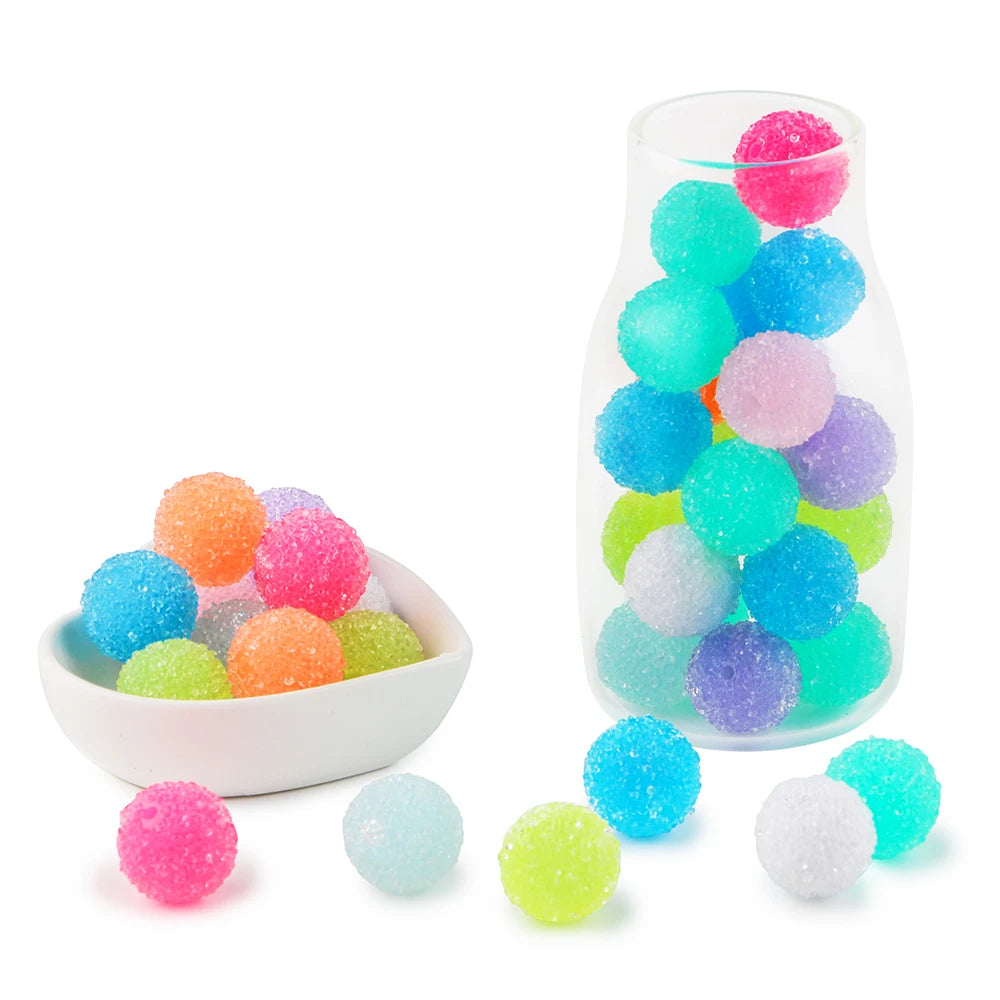 A clear glass bottle filled with colorful resin beads of various sizes and colors like pink, blue, green, and purple.