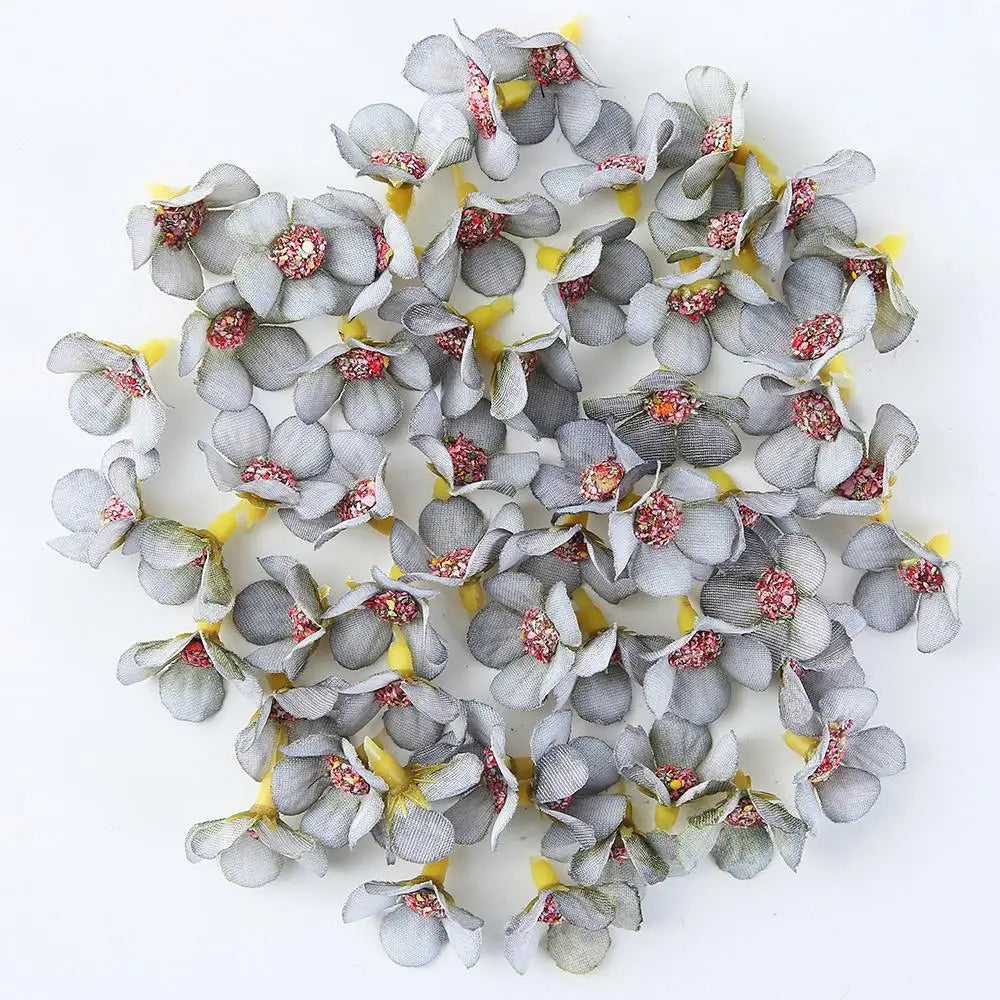 A collection of small, gray and pink silk artificial flower heads used for weddings, crafts, and home decor.