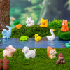 A set of mini animal fairy garden decor featuring rabbits, a pig, a cat, and other small woodland creatures on green moss.