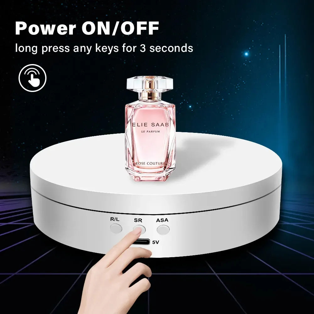 A hand presses a button on a white rotating display stand for jewelry or items.