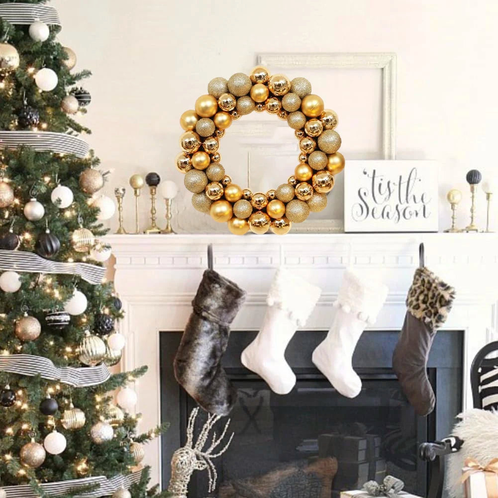 A golden silk Christmas ball wreath ornament displayed on a white mantelpiece next to a decorated Christmas tree.