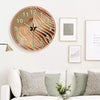 A minimalist round wall clock with wooden frame and glowing hands hanging on a white wall.