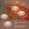 A close-up of LED floating sensor tealight candles glowing in a liquid, surrounded by colorful rose petals.