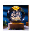 A glass crystal ball night light featuring a silhouette of Jesus and Mary with a glowing yellow light.