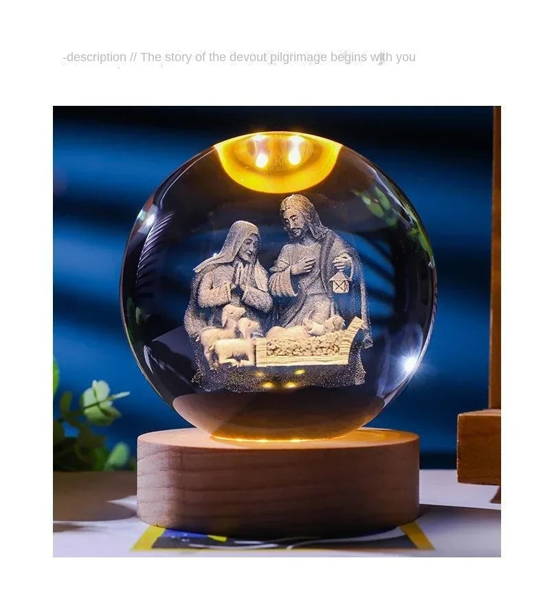 A glass crystal ball night light featuring a silhouette of Jesus and Mary with a glowing yellow light.