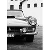 Schwarz-weißes Foto eines klassischen Autos mit offenem Motorhaube vor einem weißen Gebäude.