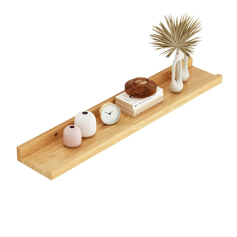 A natural wood floating shelf displaying various decorative items including a clock, spherical vases, and a dried palm frond.