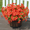A vibrant bouquet of artificial flowers in shades of red and orange potted in a dark brown container.