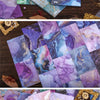 A display of gradient wash retro decorative paper in various shades of purple, blue, and pink on a wooden surface.