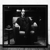 Black and white portrait of a man in a suit sitting in an armchair, resembling a classic movie poster.