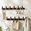 Walnut wood coat rack with eight hooks and a storage shelf mounted on a white wall.