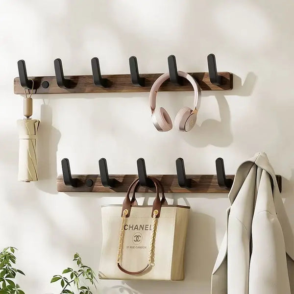 Walnut wood coat rack with eight hooks and a storage shelf mounted on a white wall.