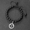 A black beaded bracelet with a silver zodiac charm is displayed on a dark surface.