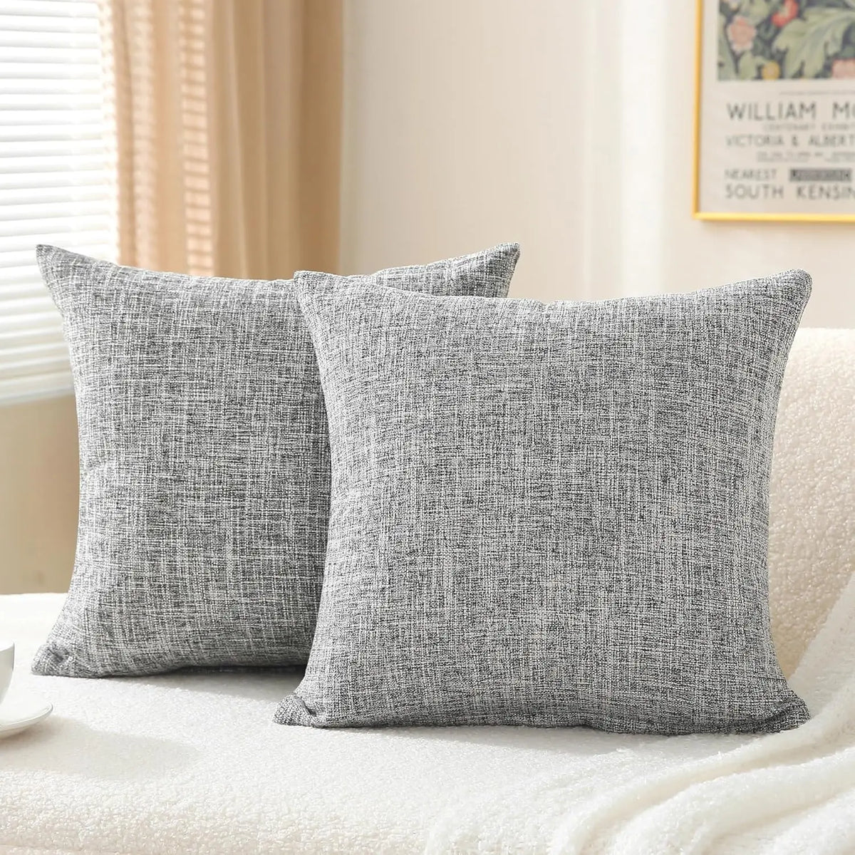 A set of two solid gray linen pillows resting on a white textured surface.