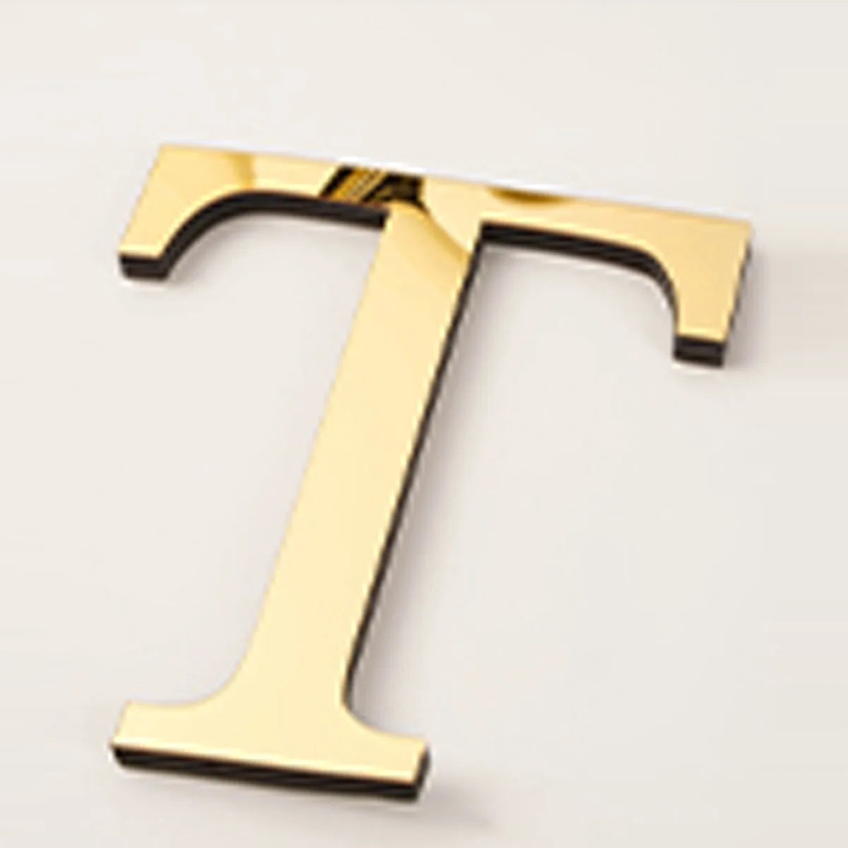 A gold acrylic mirror letter T wall sticker, 20cm in size.