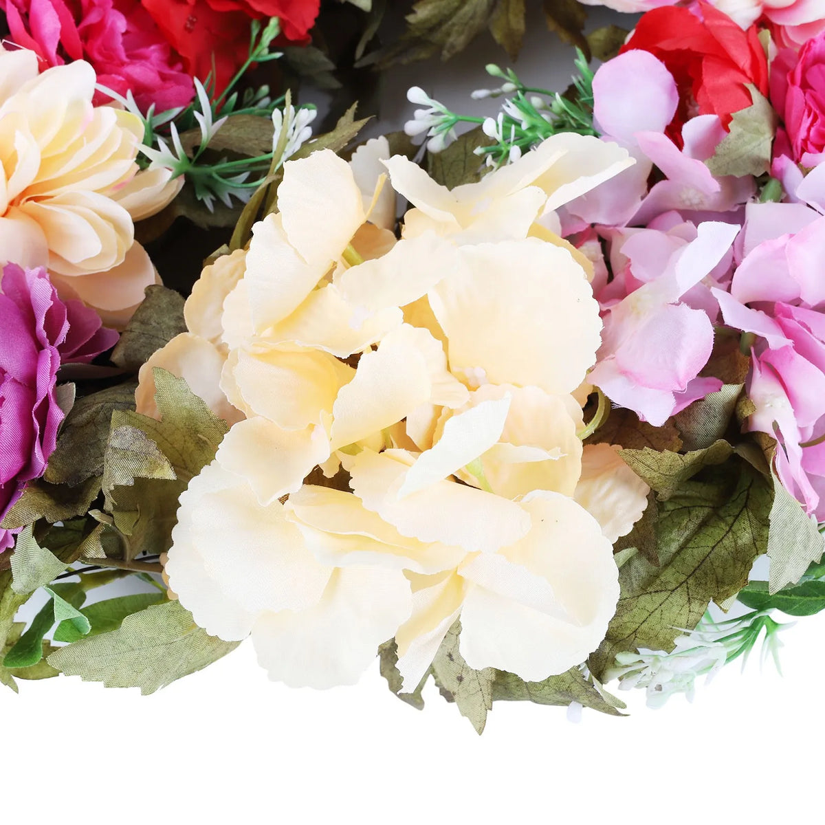 A close-up of artificial hydrangea flowers in shades of pink, red, and cream arranged for wreath decor.