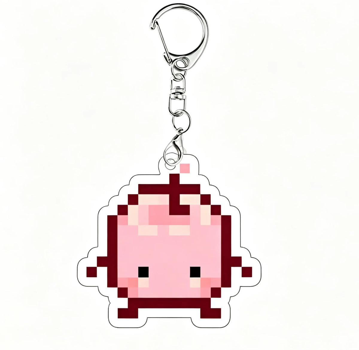 A pink pixel art charm of a Junimo character attached to a silver keychain ring.