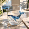 A clear glass wine glass filled with blue-colored octopus decor resting on a marble surface.