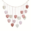 Handwoven pink leaf tassels hanging from a string, used as a wall decoration.