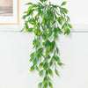 Artificial ivy garland with a pot hanging vertically against a white wall.