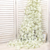 A vertical arrangement of white artificial sakura flowers cascading down, set against a light wooden slatted background.