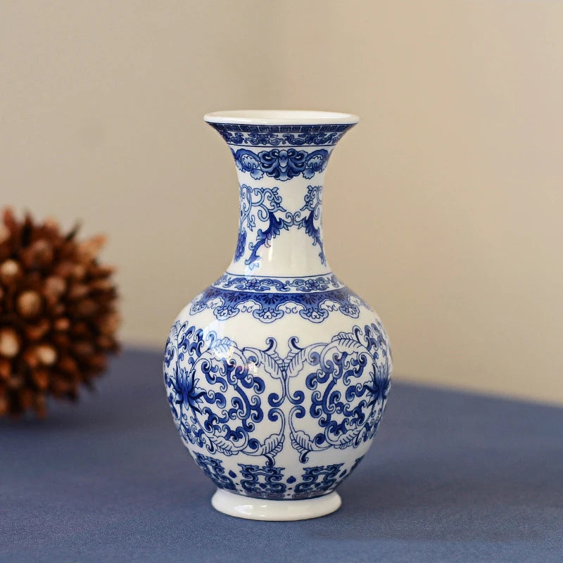 Blue and white ceramic flower vase with ornate scrolling patterns on a blue cloth.