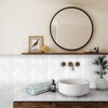 A kitchen or bathroom countertop featuring a white vessel sink and a marble backsplash with a wooden vanity.