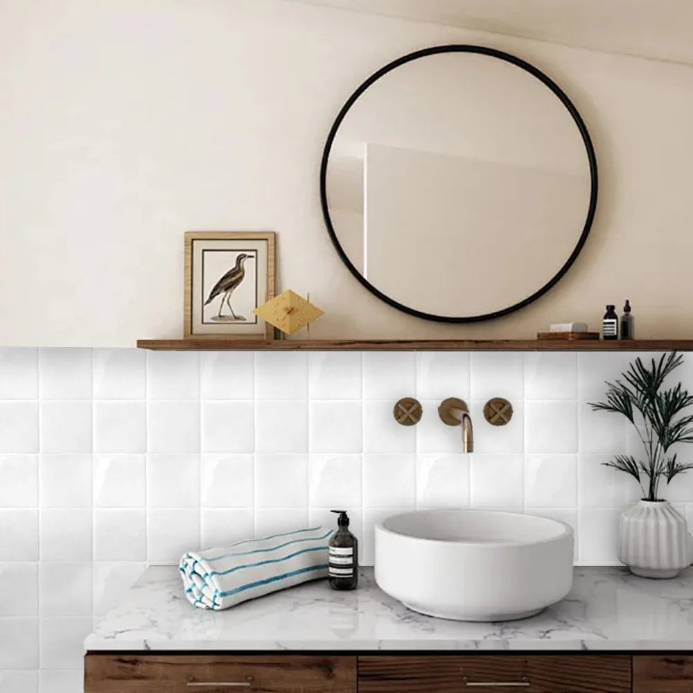 A kitchen or bathroom countertop featuring a white vessel sink and a marble backsplash with a wooden vanity.