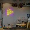 A glowing yellow bell-shaped neon sign hangs on a shelf in a kitchen setting.