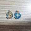 A pair of silver-toned religious pendants featuring St. Benedict imagery and a cross design on blue enamel.