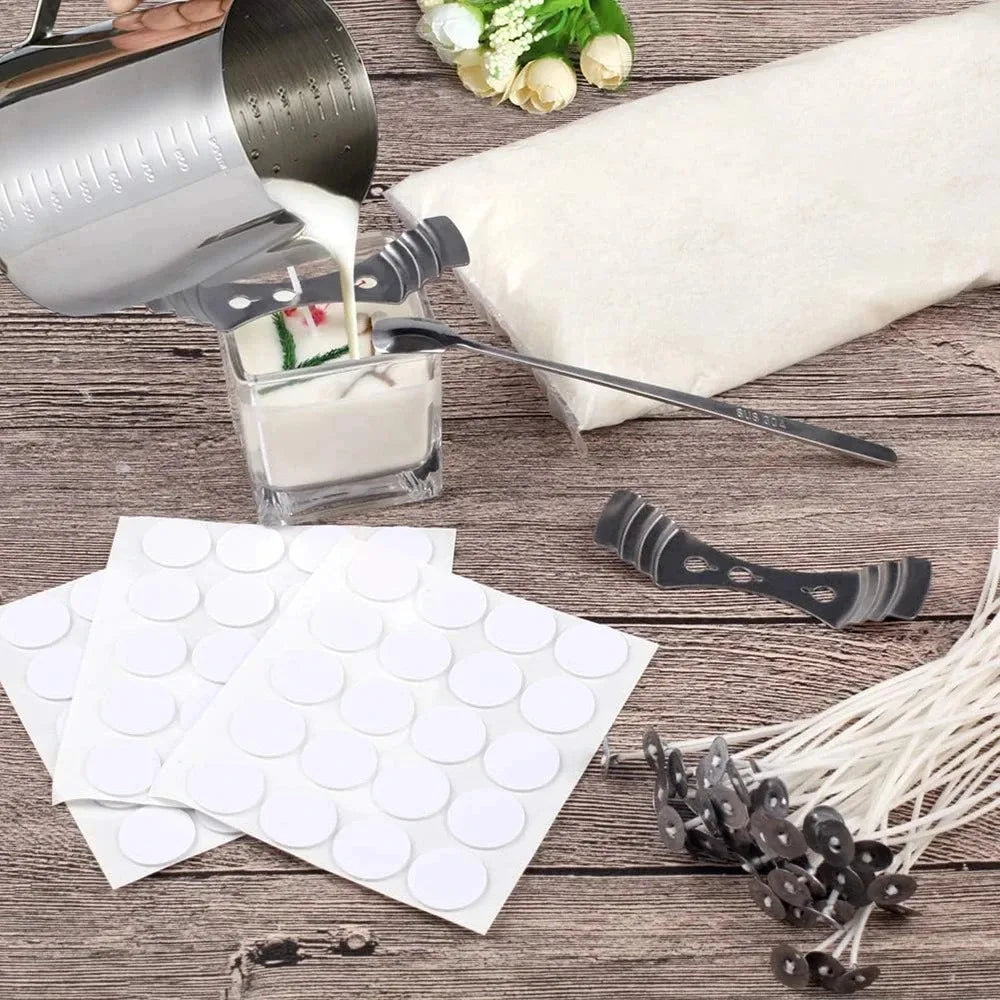 A candle making kit showing a metal melting pot, pouring pitcher, wax, and white wax pellets on a wooden surface.