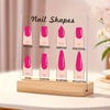 A transparent acrylic display board showing various nail shapes like round, square, arrow, and stiletto on a wooden base.