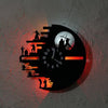 A wall clock featuring a silhouette design with an orange glow on a gray textured wall.