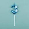 A blue number three candle with a white stick against a light teal background.