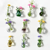 A collection of magnetic glass flower vases in various shades of green and pink displayed against a white background.