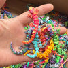 A hand holds a colorful 3D printed articulated gecko desk toy with vibrant scales and limbs.