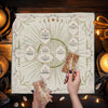 Hands hold a Celtic Cross altar cloth for tarot and divination laid on a wooden surface.