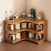 A wooden three-tier corner shelf with bamboo inserts used for storing various items like jars, books, and small plants.