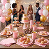 A table set featuring pink scalloped paper plates, cupcakes, and various colorful drinks for a birthday celebration.