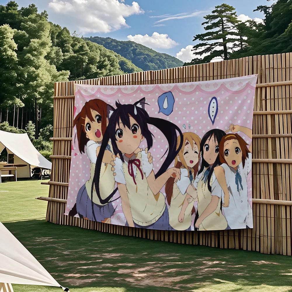 A tapestry featuring characters from the K-On! anime, including Mio, Ritsu, and others, displayed outdoors against a bamboo f