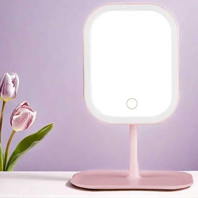 A pink smart LED makeup vanity mirror with a round light and stand on a white surface.