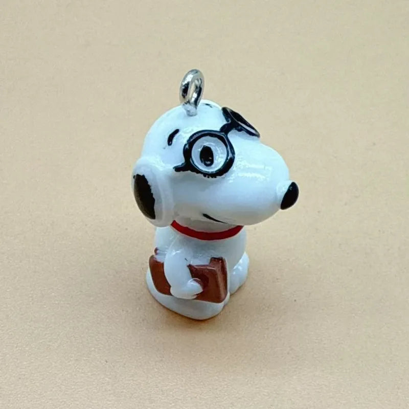 A white ceramic dog pendant with black eyes and a red collar, featuring a brown rectangular item.