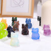 Collection d'ornements de chats en cristal sculptés à la main, de diverses couleurs et nuances, présentés sur une surface bla