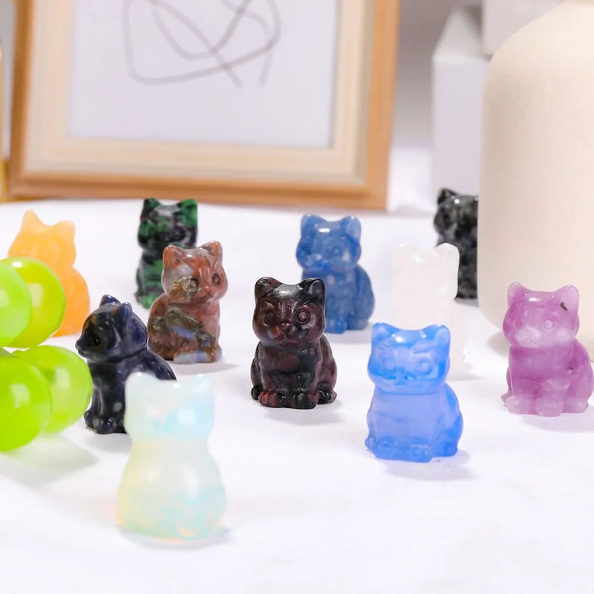 Collection d'ornements de chats en cristal sculptés à la main, de diverses couleurs et nuances, présentés sur une surface bla