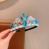 A silver crown headband adorned with blue and clear faux gems and pearls being held by a hand.