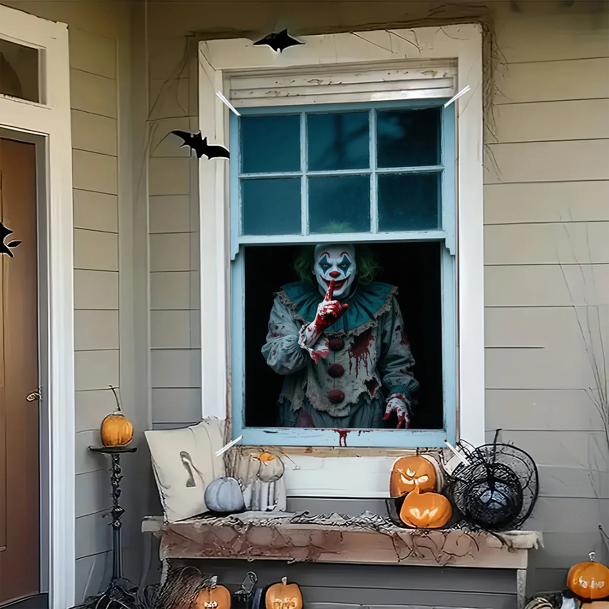 A window display featuring a clown figure with green hair and blood on a Halloween-themed banner.