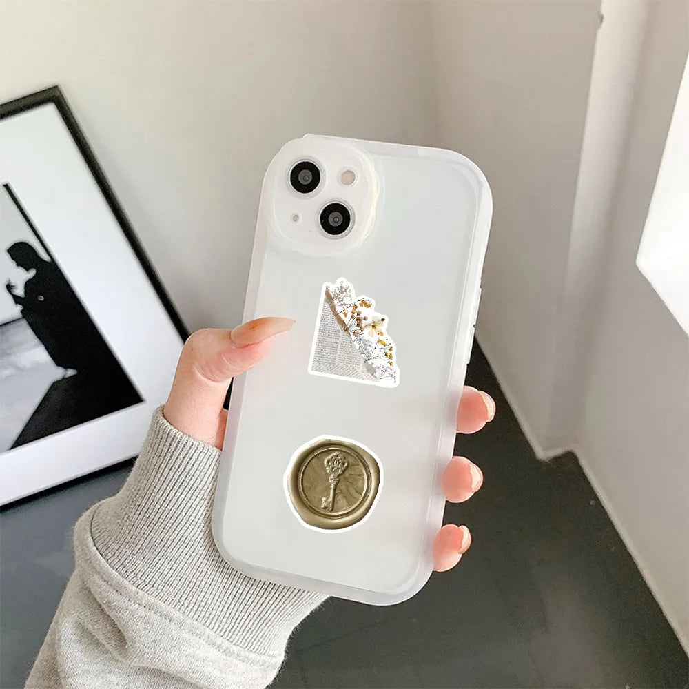 A hand holds a white smartphone displaying decorative graffiti stickers on the back panel.