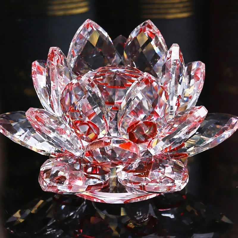 A clear pink crystal lotus flower ornament resting on a dark reflective surface.