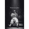 Black and white photo of a basketball player in a white jersey sitting on the court with a spotlight above him.