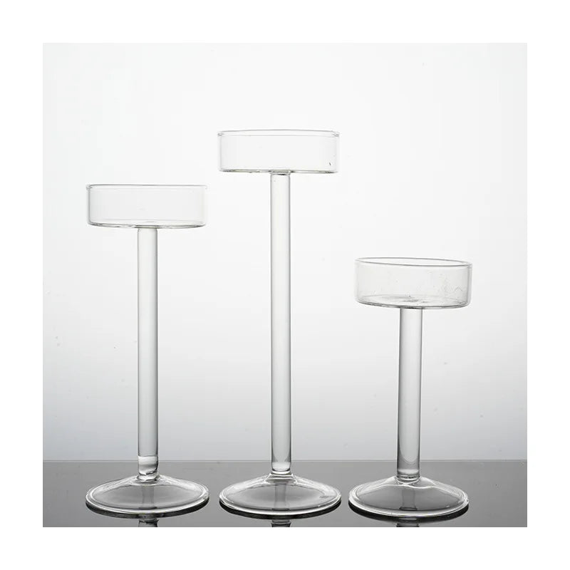 Three clear crystal glass candle holders with slender stems and round bases.
